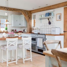 Biela kuchyne s drevenou doskou a priznanými trámy